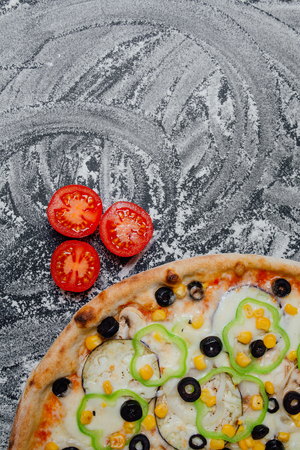Pizza with olives, tomato cherry, onion.  Fresh italian pizza. Pizza with cheese ham peppers olives board, black background with flour, sliced peppers, Top view. Banner, close-up, copy spaceの写真素材