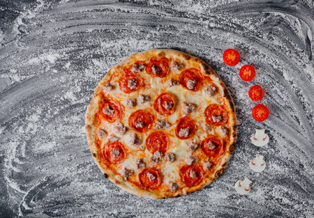 Pepperoni Pizza with Mozzarella cheese, salami, Tomatoes, pepper, decorated with sliced tomatoes and mushrooms, black background with flour, Top view. Bannerの写真素材