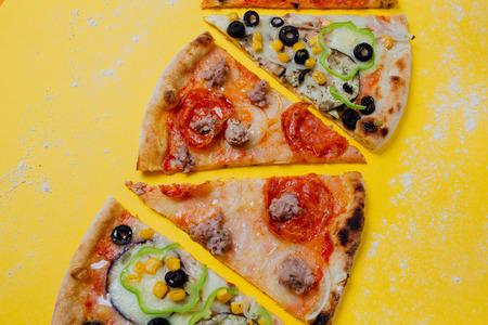 four different pizza, tasty sliced pizza,  sliced peppers, yellow background, Top view. Banner, close-up, copy-spaceの写真素材