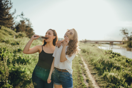 two girls eat ice cream, summer fun, in white and black shirt. with glasses, at sunset, outdoorの写真素材