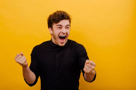 man excited, energetic, happy, screaming crying for joy, gesturing with hands,  Positive human emotion facial expression, isolated on yellow backgroundの写真素材