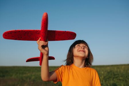 Adorable little girl holding a toy plane outdoors on sunny summer day, outdoors, sky backgroundの写真素材