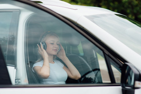 teenager relaxes with headphones listening to music, sitting in the car, outdoor