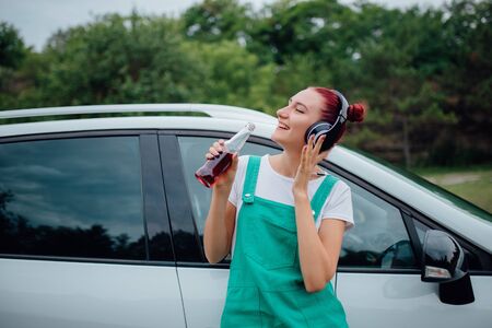 happy teens with headphones. has the drink bottle in his hand. next to the car, outdoorの写真素材