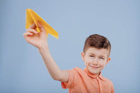 boy plays with yellow paper plane, looks at the camera,の写真素材