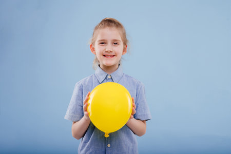 little girl with yellow balloon with smile.の写真素材