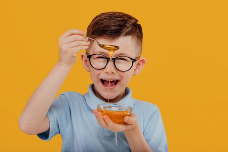 Happy boy eating fresh honeyの写真素材