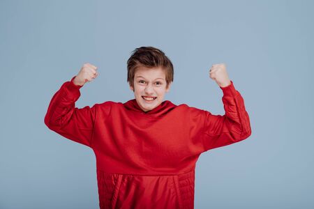 angry boy in red sweatshirt with hands up,の写真素材