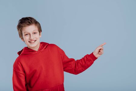 Happy kid boy in red sweatshirt pointing with fingerの写真素材