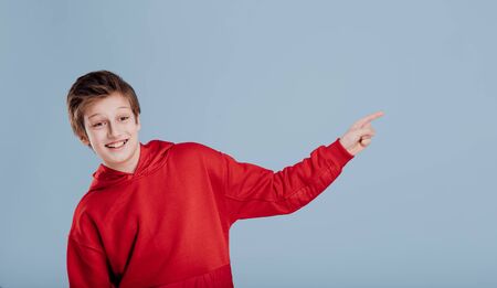 Cheerful schoolboy gesturing with finger in studioの写真素材
