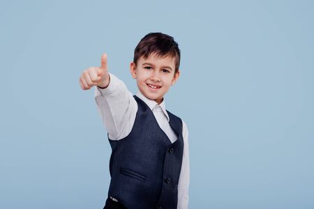 happy little kid in shirt and vest pointing with fingerの写真素材