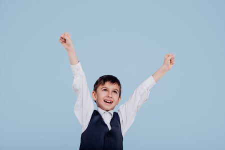 Happy kid in white shirt and vest raisingの写真素材