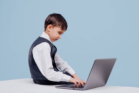 side view of curious little boy typing on laptopの写真素材