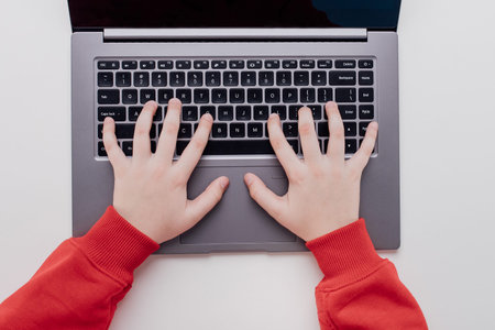 hands of a child on laptop keyboard, top view