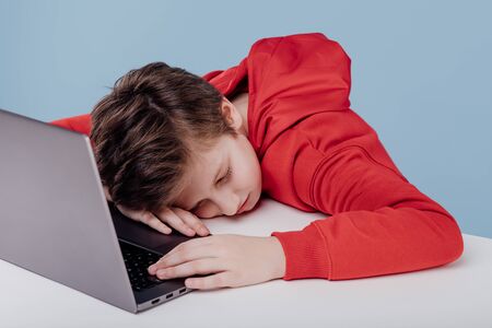 Tired preteen boy sleeping on table in studioの写真素材
