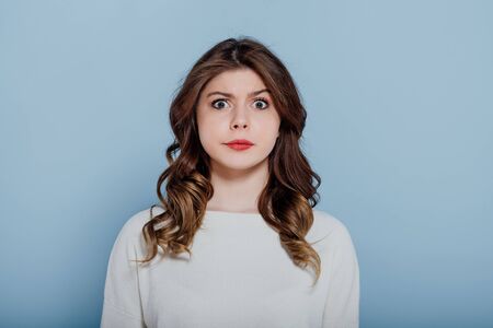 surprised girl looks at the camera, blue backgroundの写真素材