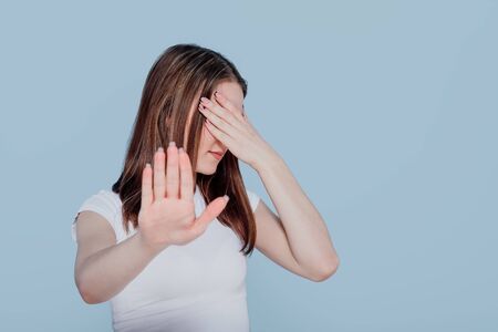 brunette girl hiding, covered eyes with hand palmの写真素材