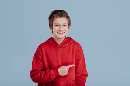 smiling teenage boy in red sweatshirt pointing with fingerの写真素材