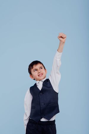 Happy child boy in white shirt and vest raisingの写真素材
