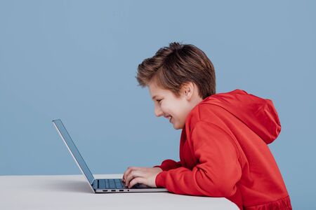 happy boy n red sweatshirt playing on laptop,の写真素材