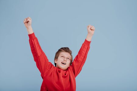 Portrait of successful teen boy winner with raised handsの写真素材