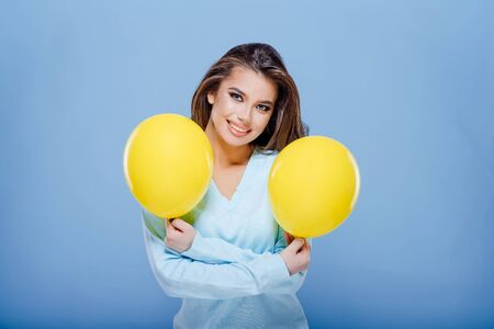 happy teenager girl is holding two yellow balloonsの写真素材