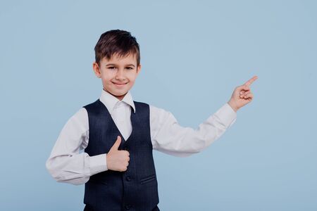 smiling little schoolboy in shirt and vest pointingの写真素材