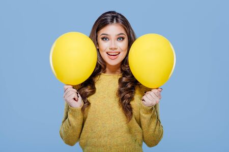Happy woman with yellow balloons blue backgroundの写真素材