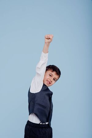 Happy child in white shirt and vest raisingの写真素材