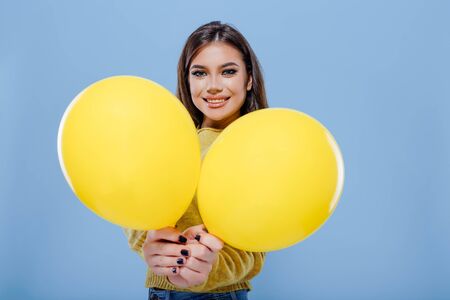 happy girl is holding yellow balloons, blue backgroundの写真素材