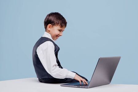 side view of curious little boy typing on laptopの写真素材