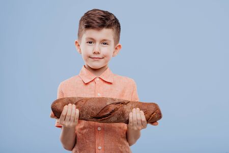 little boy holding a bread, looks at the camera,の写真素材