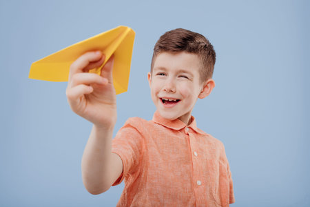 happy kid boy holds yellow paper plane in his hand,の写真素材