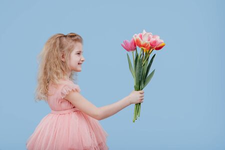 little girl in pink dress with spring flowers in handの写真素材