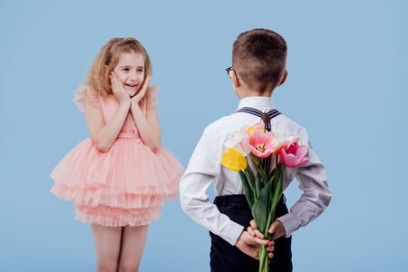 two little kids boy with flowers and surprised girl in pink dresの写真素材