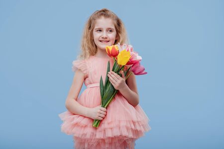 smiling little child with spring flowers tulips in her handの写真素材