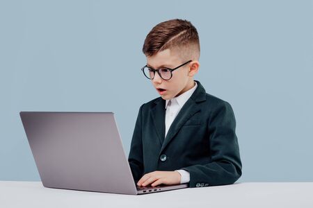 Troubled little child boy in suit and glassesの写真素材