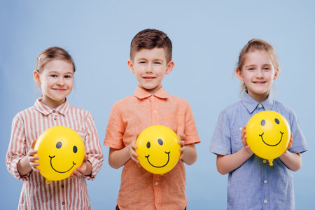 three children with yellow balloons with a smile.