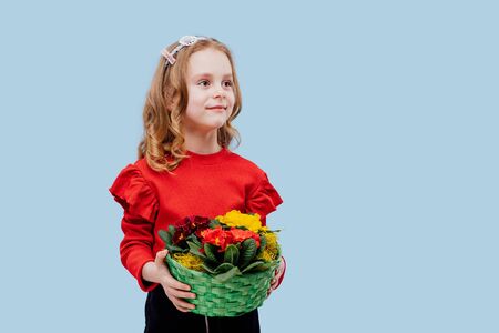 happy little girl with with basket of flowers in his handの写真素材