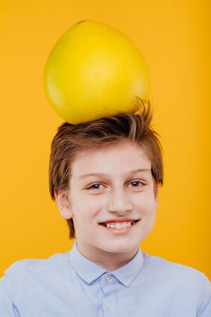 portrait preteen child boy with pomelo fruit On the headの写真素材