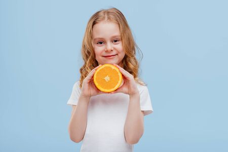 smiling little girl with an orange in her hand,の写真素材