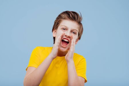 Happy teenager screaming in studio on blue backgroundの写真素材