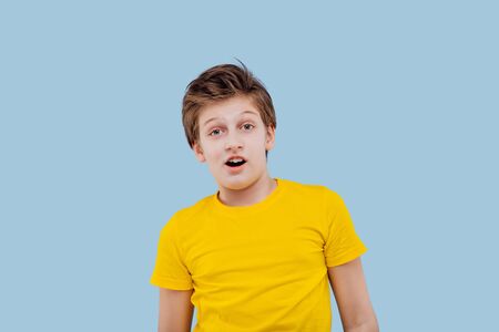 staring preteen boy in yellow t-shirt isolated on yellow background, copy space looks at cameraの写真素材