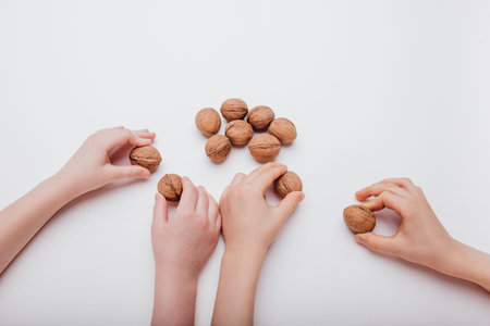 four child hand with many walnuts isolated on white background, close up, top view