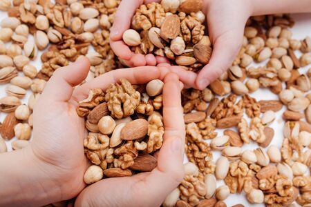 close up, Assorted nuts in the four child hands walnut, pistachio, almonds, Hazelnuts, on white background, top viewの写真素材