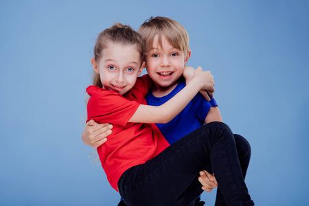 Cheerful boy carrying girl in studio isolated on blue background, in studioの写真素材