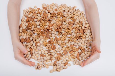 assorted nuts with two hands. walnut, pistachio, almonds, hazelnuts, on white background, top viewの写真素材