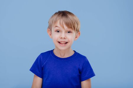 nice hapy child looks at the camera dressed in blue T-shirt, isolated on blue background, in studioの写真素材