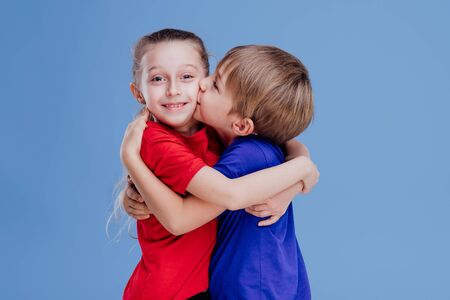 little boy kissing on the cheek on the little girl isolated on blue background, in studioの写真素材