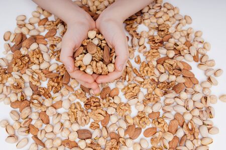 Mixed nuts in the child hands walnut, pistachio, almonds, Hazelnuts, on white background, top viewの写真素材